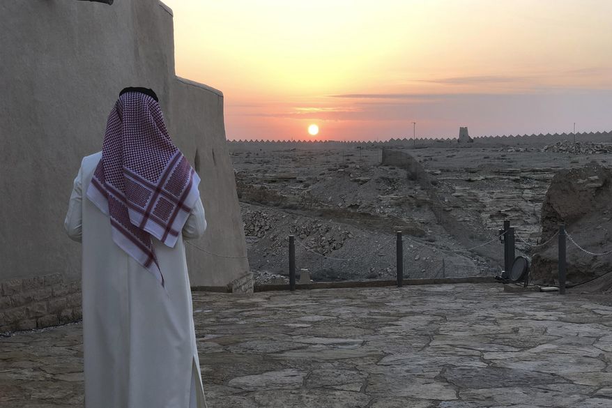FILE - In this Dec. 16, 201, file photo, a man watches the sun setting over Dhiriyah, a UNESCO World Heritage site that includes a 17th-century fortress, mosques and clay-colored structures just outside of Saudi Arabia's capital of Riyadh. Saudi Arabia has announced a new tourist visa scheme Friday, Sept. 27, 2019, as part of efforts in the ultraconservative Muslim kingdom to diversify its economy and reduce dependence on oil. (AP Photo/Karin Laub, File)