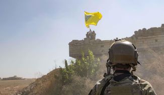 In this Sept. 21, 2019, photo, released by the U.S. Army, a U.S. soldier oversees members of the Syrian Democratic Forces as they demolish a Kurdish fighters&#39; fortification and raise a Tal Abyad Military Council flag over the outpost as part of the so-called &amp;quot;safe zone&amp;quot; near the Turkish border. (U.S. Army photo by Staff Sgt. Andrew Goedl via AP)