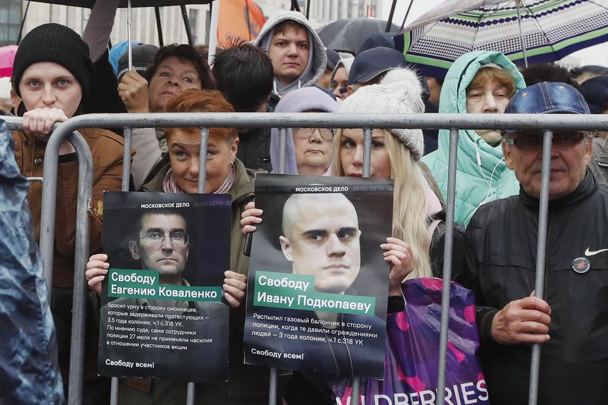 People hold portraits with signs reading from left: "Freedom to Yevgeny Kovalenko" and "Freedom to Ivan Podkopaev" during a rally to support political prisoners in Moscow, Russia, Sunday, Sept. 29, 2019. (AP Photo/Dmitri Lovetsky)