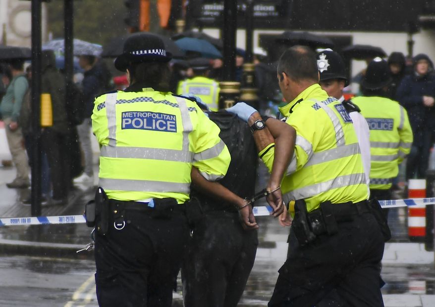 Police and medics respond to an incident outside the gates of the Houses of Parliament, in London, Tuesday, Oct. 1, 2019. Police in London have detained a man near the Houses of Parliament after he doused himself in what appeared to be flammable liquid. (AP Photo/Alberto Pezzali)