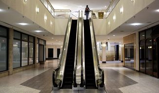 A woman rides an escalator past closed storefronts inside the largely empty White Flint Mall, Monday, Dec. 1, 2014, in Bethesda, Md. Opened in 1977, just two tenants remain as the mall&#x27;s owner plans to eventually replace it with a mix of housing, office space and outdoor shopping. (AP Photo/Patrick Semansky)