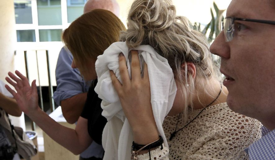 A 19-year old British woman, center, covers her face as she arrives at the Famagusta court for the first day of her trial, in Paralimni, Cyprus, Wednesday, Oct. 2, 2019. The 19 year old British woman pleaded not guilty to making up an accusation that she was raped by a dozen Israelis at a hotel in a Cypriot resort town. (AP Photo/Petros Karadjias)