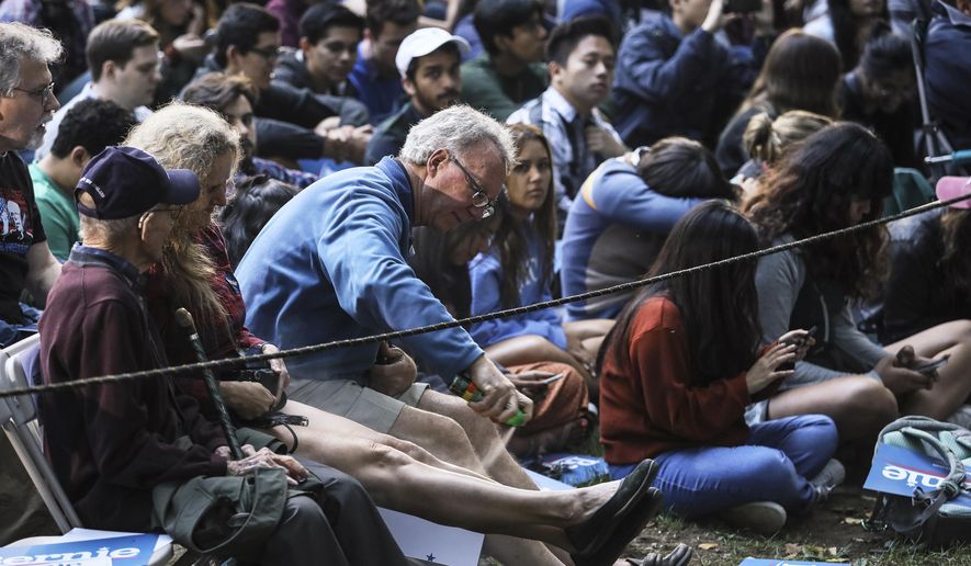 Attendees use bug spray fight off mosquitos while waiting for Democratic presidential candidate Sen. Bernie Sanders, I-Vt., to arrive at a campaign event Sunday, Sept. 29, 2019 at Dartmouth College in Hanover, N.H. (AP Photo/ Cheryl Senter)