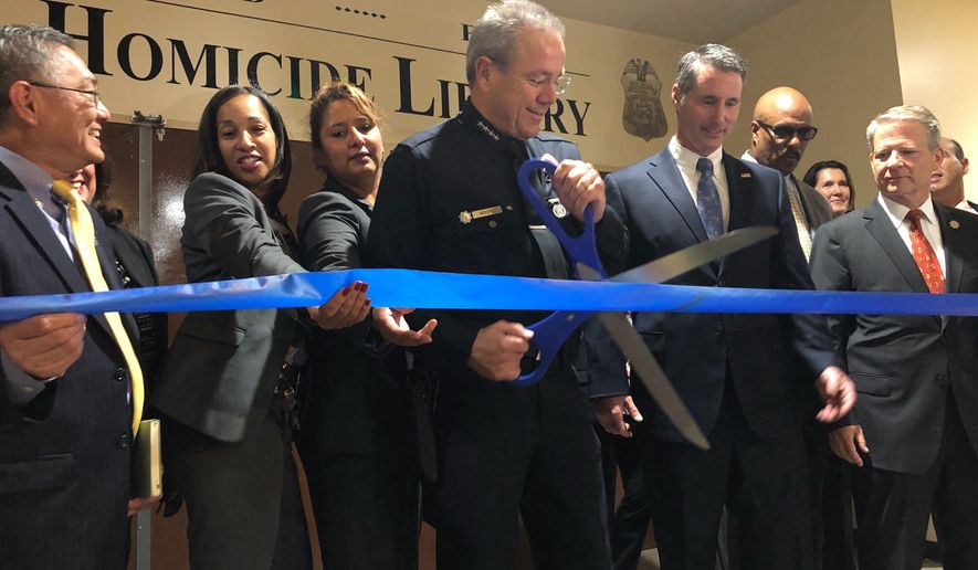 Los Angeles Police Chief Michel Moore cuts a ribbon to officially open the city's Homicide Library, where authorities are working to digitize murder cases in Los Angeles Wednesday, Oct. 2, 2019. Los Angeles authorities will open a "Homicide Library" of digital files to aid investigators who are trying to solve cold cases. Officials say Wednesday the library will house files for more than 15,000 cases to create a centralized database for what detectives call "murder books." The effort began in 2012 in one of the Los Angeles Police Department's bureaus and has become a citywide initiative with the help of the FBI. (AP Photo/Stefanie Dazio)