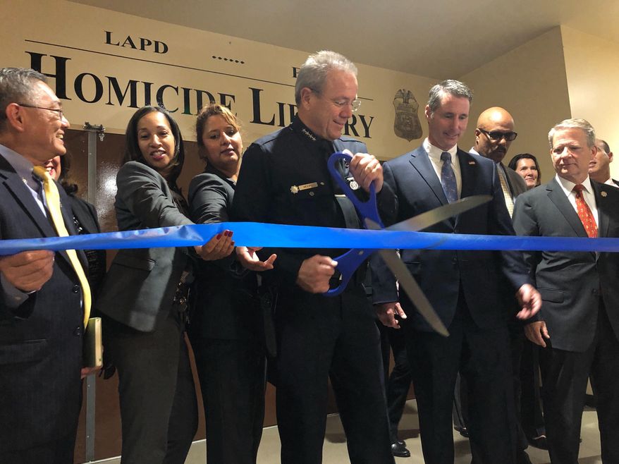 Los Angeles Police Chief Michel Moore cuts a ribbon to officially open the city's Homicide Library, where authorities are working to digitize murder cases in Los Angeles Wednesday, Oct. 2, 2019. Los Angeles authorities will open a "Homicide Library" of digital files to aid investigators who are trying to solve cold cases. Officials say Wednesday the library will house files for more than 15,000 cases to create a centralized database for what detectives call "murder books." The effort began in 2012 in one of the Los Angeles Police Department's bureaus and has become a citywide initiative with the help of the FBI. (AP Photo/Stefanie Dazio)