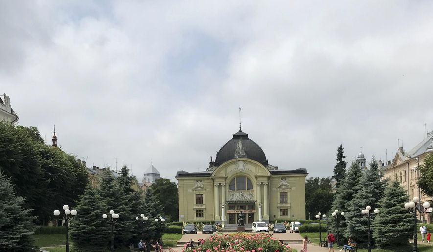This June 23, 2019 photo shows a child running in front of a bed of roses as the Chernivtsi Drama Theater stands in the background, in Chernivtsi, Ukraine. Tucked in the southwest corner of Ukraine, Chernivtsi is a cheerful city that graciously marries the glories and sorrows of centuries past with vibrant Eastern European urban life today. (AP Photo/Frances D&#x27;Emilio)