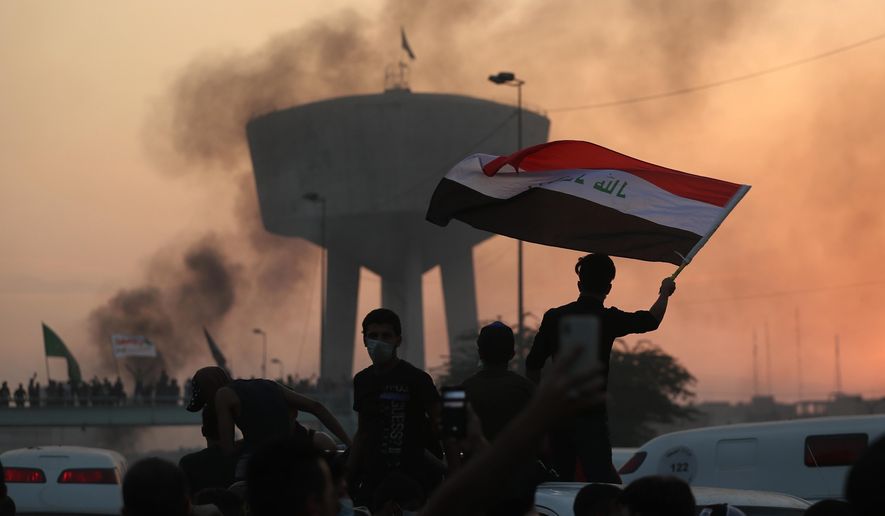 Anti-government protesters wave flags during a demonstration in Baghdad, Iraq, Wednesday, Oct. 2, 2019. Iraqi officials said several protesters have been killed Wednesday and scores injured amid gunfire and clashes in Baghdad. (AP Photo/Hadi Mizban)
