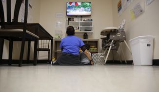A Comprehensive Health Services caregiver watches TV with a young migrant at a &amp;quot;tender-age&amp;quot; facility for babies, children and teens, in Texas&#39; Rio Grande Valley, Thursday, Aug. 29, 2019, in San Benito, Texas.  (AP Photo/Eric Gay) **FILE**
