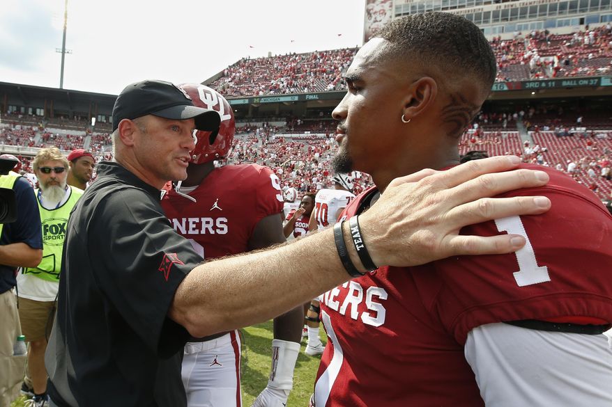 Texas Tech head coach Matt Wells, left, talks with Oklahoma quarterback Jalen Hurts (1) following their NCAA college football game in Norman, Okla., Saturday, Sept. 28, 2019. (AP Photo/Sue Ogrocki)