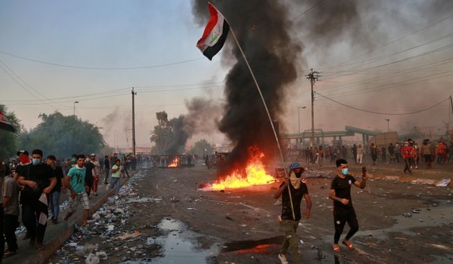 Anti-government protesters set fires and close a street during a demonstration in Baghdad, Iraq, Thursday, Oct. 3, 2019. Iraqi security forces fired live bullets into the air and used tear gas against a few hundred protesters in central Baghdad on Thursday, hours after a curfew was announced in the Iraqi capital on the heels of two days of deadly violence that gripped the country amid anti-government protests that killed over 19 people in two days. (AP Photo/Hadi Mizban)