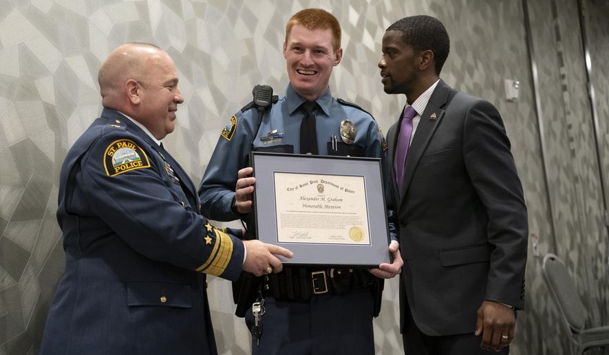 In this April 22, 2019 photo, St. Paul Police Officer Alexander Graham is presented with an honorable mention award for Officer of the Year from St. Paul Police Chief Todd Axtell, left, and St. Paul Mayor Melvin Carter in St. Paul, Minn. Mayor Carter demanded an internal police investigation into the arrest of a 13-year-old black girl, after video showing her shrieking and struggling as two white, male officers try to handcuff her sparked an angry backlash on social media. One of the officers, Alexander Graham, is the subject of an internal affairs investigation, but it’s not clear if it’s related to the girl’s arrest, the St. Paul Pioneer Press reported. (Renee Jones Schneider/Star Tribune via AP)