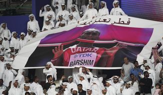 Spectators hold up a poster of high jumper Mutaz Essa Barshim, of Qatar, at the World Athletics Championships in Doha, Qatar, Friday, Oct. 4, 2019. (AP Photo/David J. Phillip)