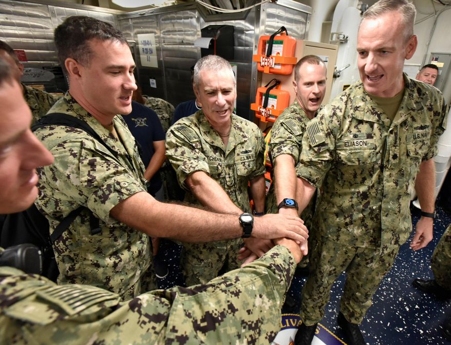 In a Friday, September 27, 2019 photo, Cdr. Pat Eliason, right, Commanding Officer of the USS The Sullivans and Rear Admiral Roy Kitchener, center, join crew members in cheering the ship's motto, "We Stick Together" during a reunion of family members and former crew members at Mayport Naval Station, Florida. The ship is a guided missile destroyer named for five Sullivan brothers who died when their ship, the USS Juneau was sunk by a Japanese submarine in World War II. (Will Dickey/The Florida Times-Union via AP)