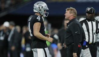 Oakland Raiders head coach Jon Gruden, front right, talks with quarterback Derek Carr (4) during the first half of an NFL football game against the Chicago Bears at Tottenham Hotspur Stadium, Sunday, Oct. 6, 2019, in London. (AP Photo/Kirsty Wigglesworth)