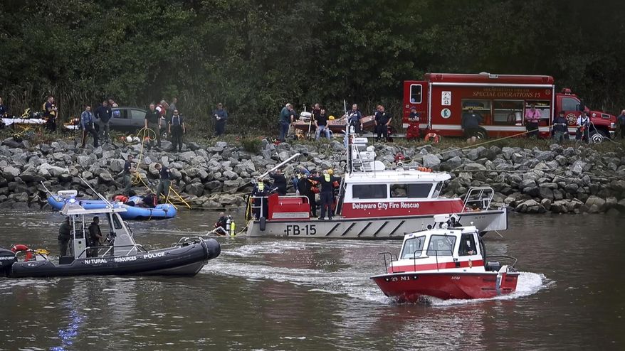 Emergency personnel, including divers, work on the Chesapeake & Delaware Canal where a vehicle plunged into the water from South Canal Road, west of St. Georges, Del., Sunday, Oct. 6, 2019. (William Bretzger/The News Journal via AP)