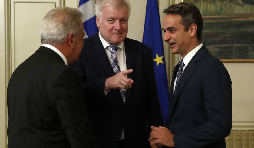 Greece's Prime Minister Kyriakos Mitsotakis, right, German Interior Minister Horst Seehofer, center, and EU migration commissioner Dimitris Avramopoulos talk during their meeting at Maximos Mansion in Athens, Friday, Oct. 4, 2019. Greece said Friday it will call on the European Union to impose sanctions on member states that refuse to accept refugees, as senior European officials visited Ankara and Athens to try and stem a surge in migrant arrivals overwhelming Greek islands. (AP Photo/Thanassis Stavrakis)