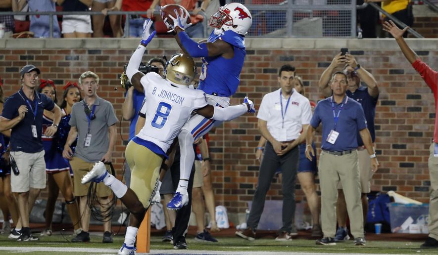 SMU wide receiver James Proche, in blue, catches a touchdown pass while Tulsa safety Brandon Johnson (8) defends during the third overtime of an NCAA college football game Saturday, Oct. 5, 2019, in Dallas, Texas. SMU beat Tulsa 43-37. (AP Photo/Roger Steinman)