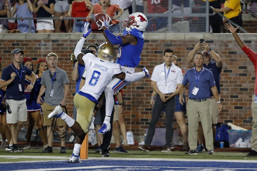 SMU wide receiver James Proche, in blue, catches a touchdown pass while Tulsa safety Brandon Johnson (8) defends during the third overtime of an NCAA college football game Saturday, Oct. 5, 2019, in Dallas, Texas. SMU beat Tulsa 43-37. (AP Photo/Roger Steinman)
