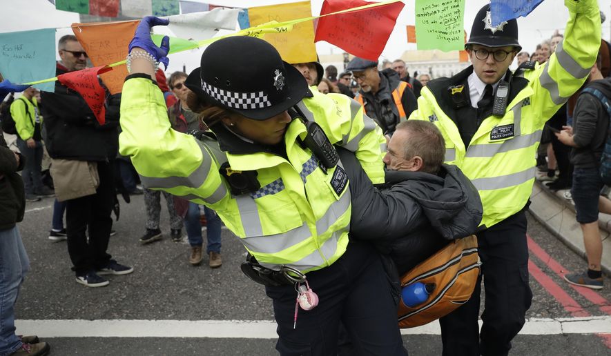 Police officer remove a climate protestor from Lambeth bridge in central London Monday, Oct. 7, 2019. Environmentalist blocked roads leading to Britain's Parliament in an attempt to disrupt the heart of government. (AP Photo/Matt Dunham)