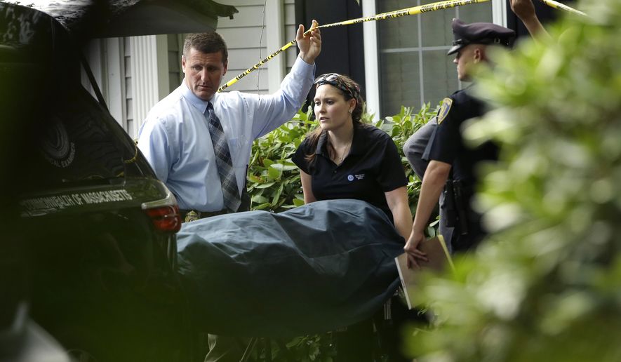 A woman from the Massachusetts Chief Medical Examiners Office, center, uses a gurney to place human remains into a vehicle as law enforcement officers hold caution tape at a home where two adults and three children were found dead with gunshot wounds, Monday, Oct. 7, 2019, in Abington, Mass. (AP Photo/Steven Senne)