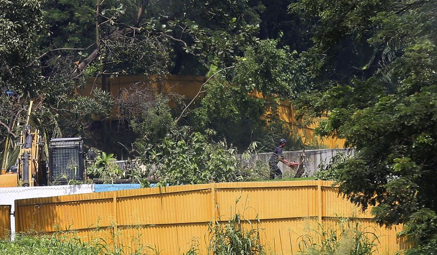 A man cuts a tree branch at the construction site of a metro train parking shed at Aarey Colony, Mumbai, India, Monday, Oct, 7, 2019. India's Supreme Court has ordered the government of the Indian state of Maharashtra to stop tree-felling after protesters swarmed the area. The court order on Monday stalls tree-cutting at least until another hearing October 21. (AP Photo/Rafiq Maqbool)