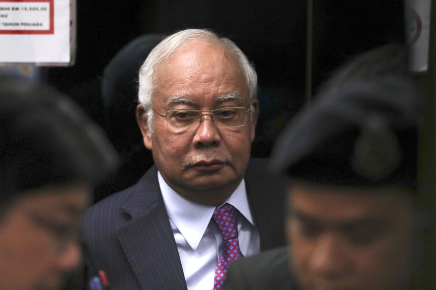 FILE - In this June 18, 2019, file photo, former Malaysian Prime Minister Najib Razak walks into the lift as he arrives at Kuala Lumpur High Court in Kuala Lumpur, Malaysia. Malaysia has ordered 80 people and groups to pay fines totaling about $100 million for allegedly receiving funds from the 1MDB state investment fund. Najib faces 42 charges of corruption, abuse of power and money laundering in five separate criminal cases linked to the multibillion-dollar looting of 1MDB. (AP Photo/Vincent Thian, File)
