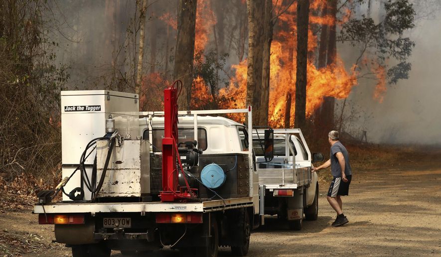 A local resident gets into his vehicle near a bushfire burning near Busbys Flat, Australia, Wednesday, Oct. 9, 2019. Parts of Australia's east suffered widespread fire damage with up to 30 homes destroyed as out-of-control wildfires continued to ravage northern New South Wales state. (Jason O'Brien/AAP Image via AP)