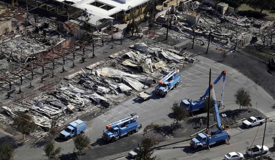 FILE - In this Oct. 14, 2017, file photo, PG&E crews work on restoring power lines in a fire ravaged neighborhood in an aerial view in the aftermath of a wildfire in Santa Rosa, Calif. PG&E says it could cut off power to a large swath of Northern California later this week to prevent its equipment from starting wildfires during hot, windy weather. The utility says power could be shut off in 30 counties in central and Northern California starting Wednesday, Oct. 9, when hot weather and strong winds are forecast, and through Thursday. (AP Photo/Marcio Jose Sanchez, File)