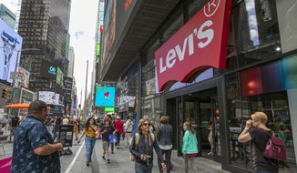 FILE - In this June 14, 2019, file photo people pass the Levi&#39;s store in in New York&#39;s Times Square. Levi Strauss &amp;amp; Co. reports earns Tuesday, Oct. 8. (AP Photo/Richard Drew, File)