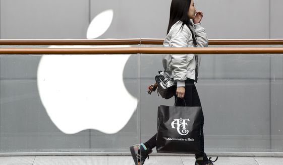 In this Feb. 26, 2019, file photo, a woman carries a paper bag containing goods purchased from American brand Abercrombie &amp;amp; Fitch walks past an Apple store at the capital city&#39;s popular shopping mall in Beijing. Companies who do business with China walk a fine line to stay aligned with U.S. values such as freedom of speech and democracy while avoiding offending China, where they stand to make billions of dollars. (AP Photo/Andy Wong, File) **FILE**