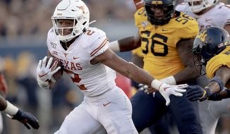 Texas running back Roschon Johnson (2) runs with the ball against West Virginia during an NCAA college football game on Saturday, Oct. 5, 2019, in Morgantown, W. Va. (Nick Wagner/Austin American-Statesman via AP)