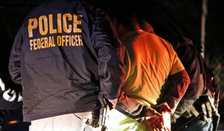 In this Oct. 22, 2018, photo U.S. Immigration and Customs Enforcement agents surround and detain a person during a raid in Richmond, Va. (AP Photo/Steve Helber) **FILE**