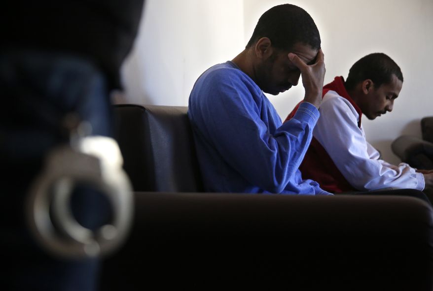 FILE - In this March 30, 2018, file, photo, Alexanda Amon Kotey, left, and El Shafee Elsheikh, who were allegedly among four British jihadis who made up a brutal Islamic State cell dubbed "The Beatles," sit on a sofa during an interview with The Associated Press at a security center in Kobani, Syria. The IS could get a new injection of life if conflict erupts between the Kurds and Turkey in northeast Syria as the U.S. pulls its troops back from the area. The White House has said Turkey will take over responsibility for the thousands of IS fighters captured during the long campaign that defeated the militants in Syria. But its not clear how that could happen. (AP Photo/Hussein Malla, File)
