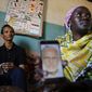Gerald Erebon sits with his aunt, Scolastica Apayo, as she holds a phone displaying a photo of the Rev. Mario Lacchin, during an interview at her home in the Isiolo area of the Archers Post settlement in Kenya on Sunday, June 30, 2019. Scolastica said her sister, Sabina Losirkale, finally told her the secret in 2012, two weeks before she died. “Now that my days are over,” her sister told her, she could reveal all: “When Gerald will ask you who’s his father, just tell him: Father Mario.” (AP Photo/Brian Inganga)