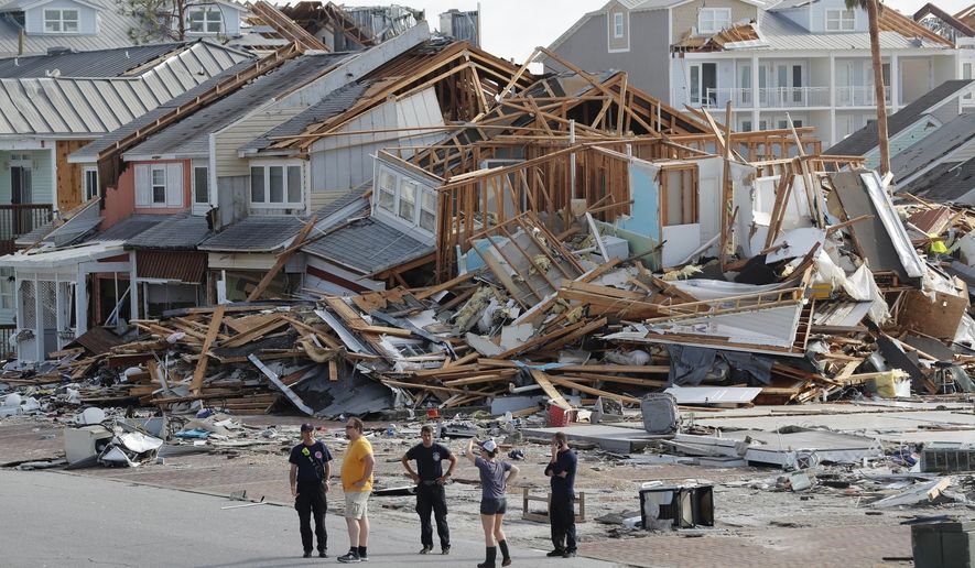 FILE- In this Oct. 11, 2018 file photo, rescue personnel perform a search in the aftermath of Hurricane Michael in Mexico Beach, Fla. A year after Hurricane Michael, Bay County, Florida, is still in crisis. Thousands are homeless, medical care and housing are at a premium, and domestic violence is increasing. Michael was among the strongest hurricanes ever to make landfall in the United States. This summer, county officials unveiled a blueprint to rebuild. Among their ideas: Use shipping containers and 3-D technology to build new houses and offer signing bonuses to lure new doctors. (AP Photo/Gerald Herbert, File)