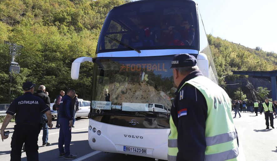 Serbian police officers guard a bus with Red Star players at the border crossing between Serbia and Kosovo, near the village of Rudnica, Serbia, Wednesday, Oct. 9, 2019. Kosovo authorities have banned a soccer match between Red Star Belgrade and a local Serb team and prevented their bus from crossing into the former Serbian province. (AP Photo/Bojan Slavkovic)