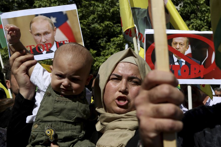 A Kurdish woman living in Cyprus holds up a baby as she shouts slogans in front of the U.S. embassy to protest Turkey's offensive into Syria, in Nicosia, Cyprus, Thursday, Oct. 10, 2019. The protesters, waving Cypriot and Kurdish flags as well as placards pledging support for Syria's Kurdish population, chanted slogans condemning Turkey's military action and urged for the withdrawal of Turkish forces. (AP Photo/Petros Karadjias)