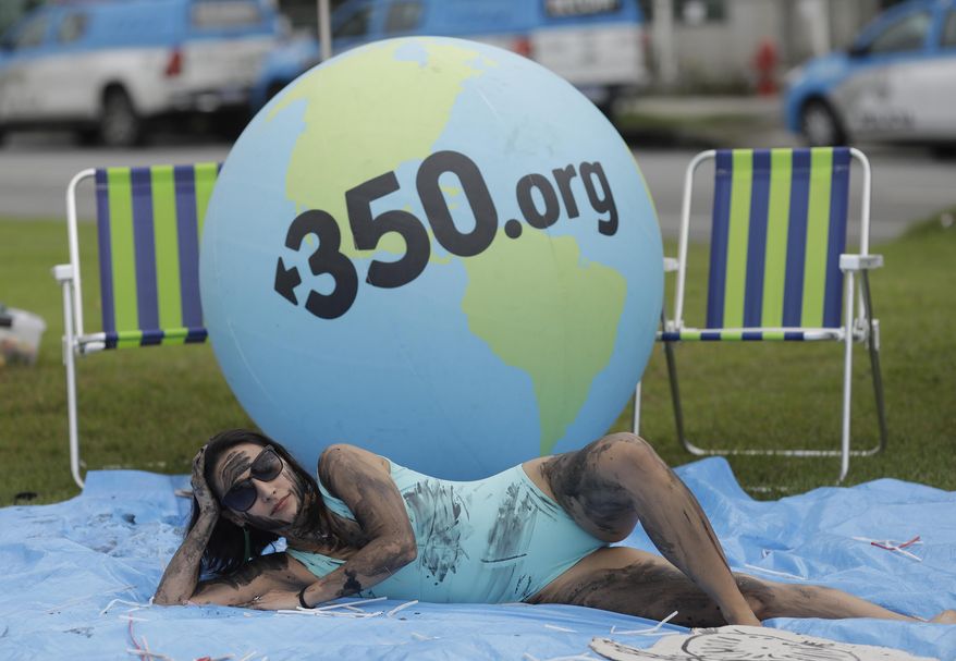 A demonstrator painted with fake oil lies on a tarp during a protest against the auction for the exploration of oil fields close to Abrolhos, a marine national park in Bahia state, in front of the Grand Hyatt Hotel where the auction is taking place, in Rio de Janeiro, Brazil, Thursday, Oct. 10, 2019. Under pressure from environmental organizations, none of the 17 companies involved in the process presented any offers. (AP Photo/Silvia Izquierdo)