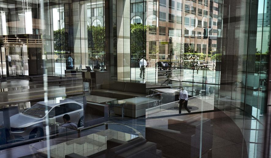 FILE - In this Aug. 27, 2018, file photo downtown Los Angeles buildings and office workers are reflected in the front windows of a building. California has proposed rules for companies preparing for the state’s data privacy bill, including setting out specific ways people can ask for their personal information to be deleted from company databases. (AP Photo/Richard Vogel, File)