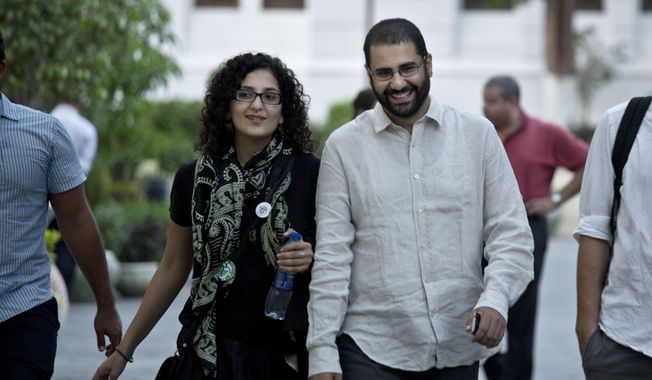 FILE - In this Sept. 22, 2014 file photo, Alaa Abdel-Fattah, a leading pro-democracy activist, walks with his sister Mona Seif prior to a conference at the American University in Cairo, near Tahrir Square, Egypt. The family of Abdel-Fattah, who was arrested amid the recent clampdown that followed anti-government protests, says he was beaten, threatened and stripped to his underwear while in custody. Seif, a prominent human rights activist tweeted on Thursday, Oct. 10, 2019, that her brother also told his lawyers that he was blindfolded and threatened that he would never set foot outside one of Cairo’s most notorious prisons. (AP Photo/Nariman El-Mofty, File)