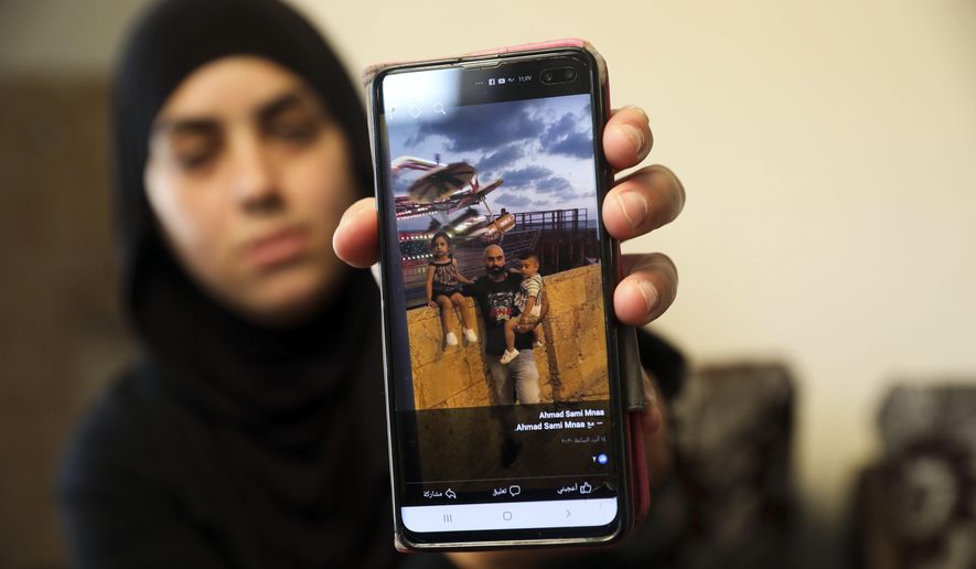 In this Monday, Oct. 7, 2019 photo, a relative shows a photo of Ahmed Manaa with his children at the family home in Majd al-Krum, Israel. Two brothers, Ahmed and Khalil Manaa, and a third man, Mohammed Sabea were recently killed in a midday shootout in Majd al-Krum, that left another Manaa brother wounded and remains in the hospital. A wave of violent crime in Israel’s Arab communities has exposed the longstanding mistrust between the marginalized community and Israeli authorities, with each side accusing the other of neglecting the problem. (AP Photo/Mahmoud Illean)