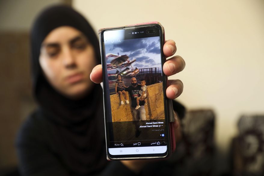 In this Monday, Oct. 7, 2019 photo, a relative shows a photo of Ahmed Manaa with his children at the family home in Majd al-Krum, Israel. Two brothers, Ahmed and Khalil Manaa, and a third man, Mohammed Sabea were recently killed in a midday shootout in Majd al-Krum, that left another Manaa brother wounded and remains in the hospital. A wave of violent crime in Israel’s Arab communities has exposed the longstanding mistrust between the marginalized community and Israeli authorities, with each side accusing the other of neglecting the problem. (AP Photo/Mahmoud Illean)