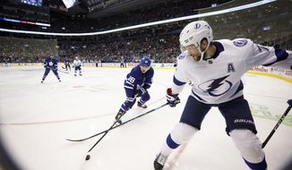 Toronto Maple Leafs center William Nylander (88) and Tampa Bay Lightning center Alex Killorn (17) reach for the puck in the corner during the second period of an NHL hockey game Thursday, Oct. 10, 2019, in Toronto. (Cole Burston/The Canadian Press via AP)