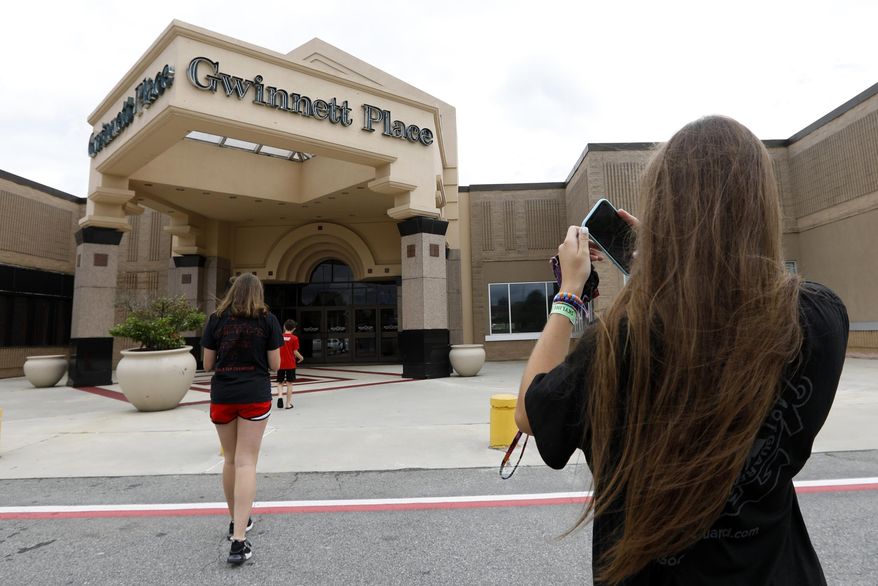 In this July 23, 2019 file photo, Brinley Rawson, a 17-year-old Stranger Things fan from Gwinnett County, snaps a photo of Gwinnett Place Mall in Duluth, Ga. The Georgia mall heavily featured in the latest season of Netflix's "Stranger Things" is going up for sale. Moonbeam Capital Partners is ready to sell its portion of the long-struggling Gwinnett Place Mall, which has been so empty that a body went unnoticed near the food court for about two weeks in 2017. (AP Photo/Andrea Smith, File) **FILE**