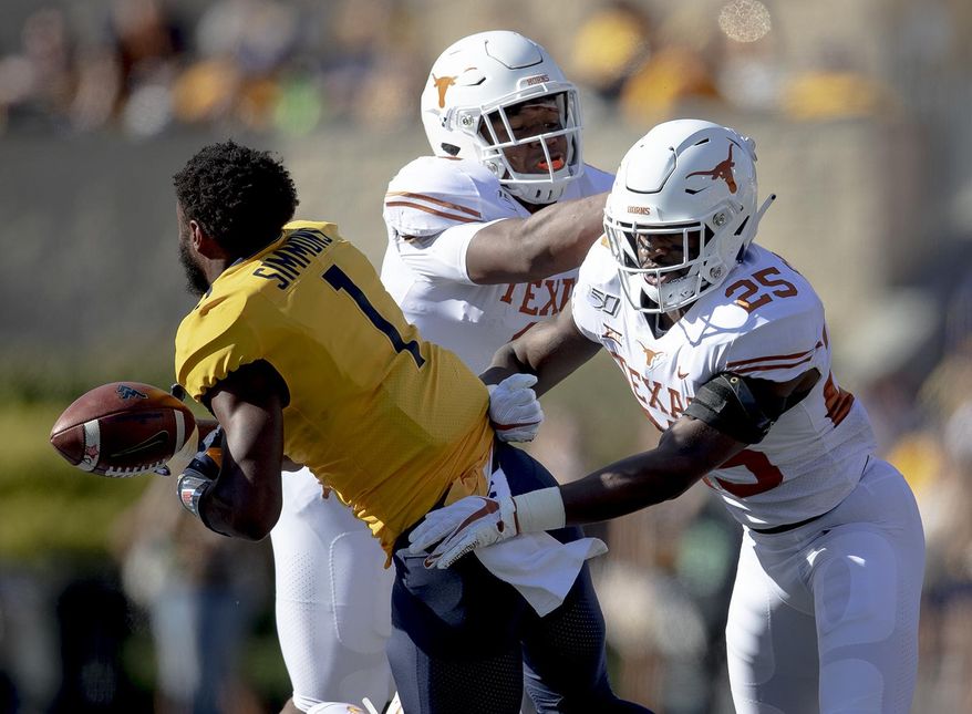 Texas defensive back B.J. Foster (25) shoves West Virginia wide receiver T.J. Simmons (1) during an NCAA college football game on Saturday, Oct. 5, 2019, in Morgantown, W.Va. (Nick Wagner/Austin American-Statesman via AP)