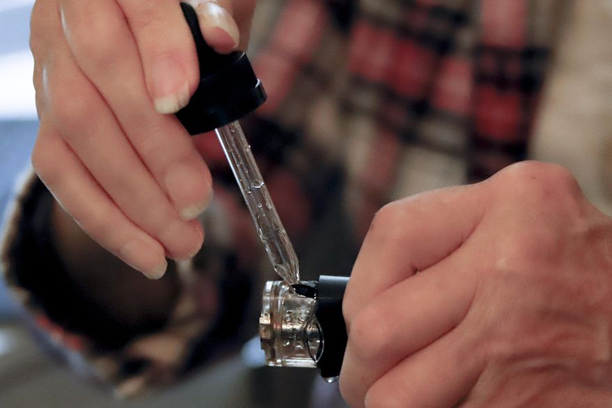 In this Friday, Oct. 4, 2019 photo, a woman loads liquid into her vaping device in Harmony, Pa. On Thursday, Oct. 10, 2019, The Centers for Disease and Prevention on said 219 vaping-related illnesses in the U.S. were reported in the past week. The number continues to rise, now reaching about 1,300 cases and at least 26 deaths. (AP Photo/Keith Srakocic)