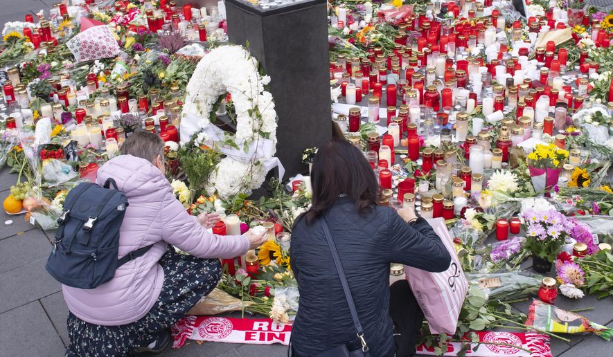 People place down flowers and candles at the marketplace in the old town of Halle, Germany, Friday, Oct. 11, 2019. A heavily armed assailant ranting about Jews tried to force his way into a synagogue in Germany on Yom Kippur, Judaism's holiest day, then shot two people to death nearby in an attack Wednesday that was livestreamed on a popular gaming site. (AP Photo/Jens Meyer)
