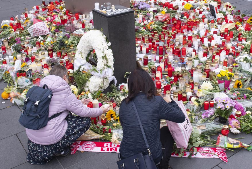 People place down flowers and candles at the marketplace in the old town of Halle, Germany, Friday, Oct. 11, 2019. A heavily armed assailant ranting about Jews tried to force his way into a synagogue in Germany on Yom Kippur, Judaism's holiest day, then shot two people to death nearby in an attack Wednesday that was livestreamed on a popular gaming site. (AP Photo/Jens Meyer)