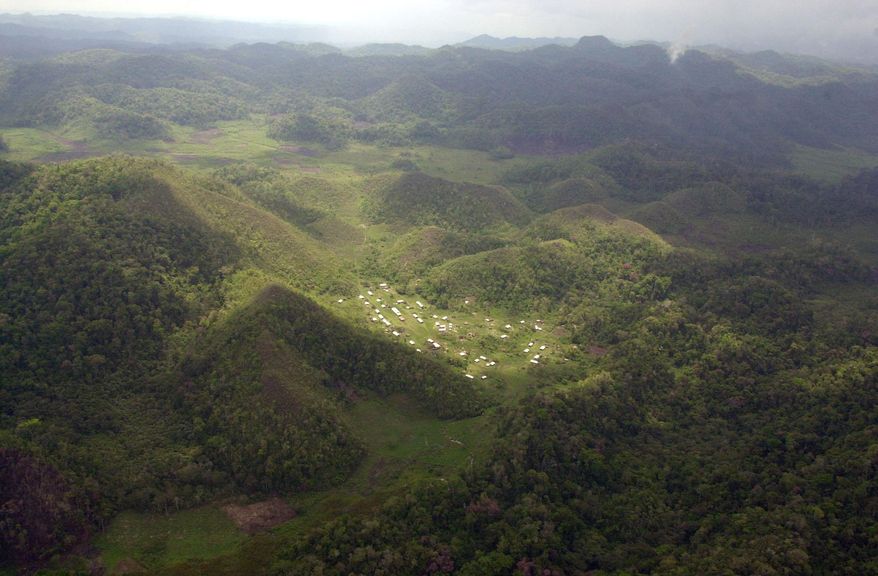 FILE – In this May 24, 2002 file photo, the community of Nuevo Pichucalco deep inside the Montes Azules nature reserve is seen from the higher peaks of the mountains, Chiapas, Mexico. Mexico's few remaining indigenous Lacandon said on Oct. 2019, that settlers are threatening their ancestral home, the last pocket of tropical rainforest in North America. (AP Photo/Eduardo Verdugo, File)