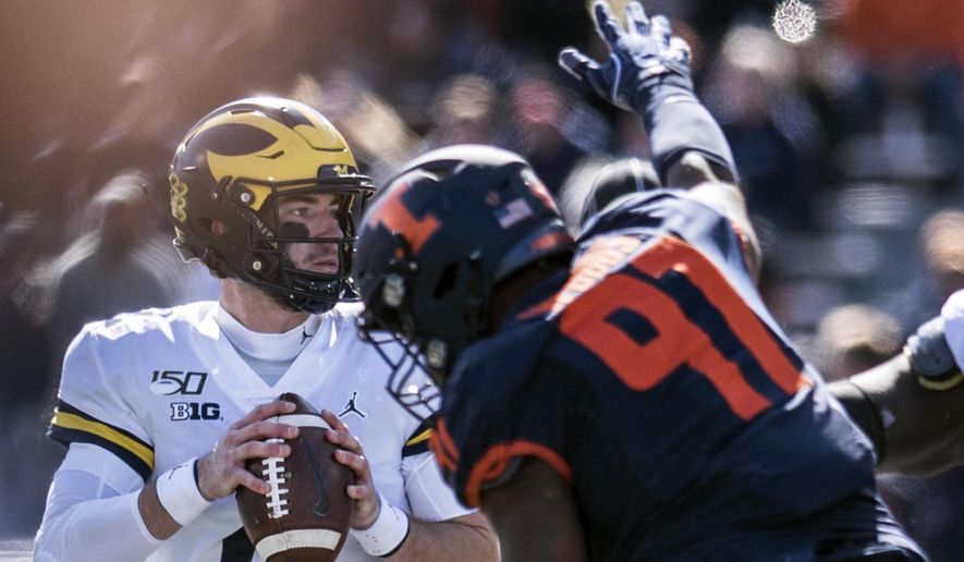 Michigan quarterback Shea Patterson (2) keeps his eye on a receiver as he is pressured by Illinois' Bobby Roundtree (97) in the second half of an NCAA college football game between Illinois and Michigan, Saturday, Oct. 12, 2019, in Champaign, Ill. (AP Photo/Holly Hart)
